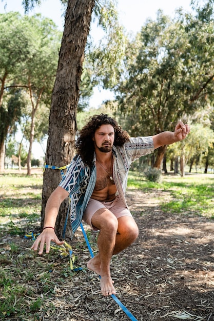 Jonge man slacklining in het stadspark tijdens zomerdag