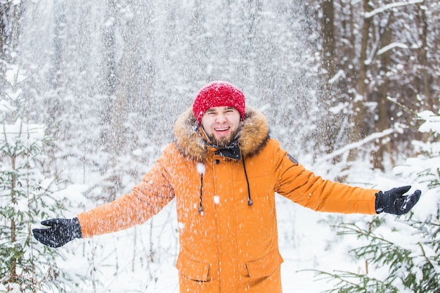 Jonge man sneeuw gooien in winter woud.