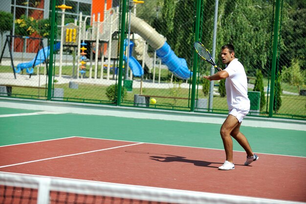 jonge man speelt tennis buiten