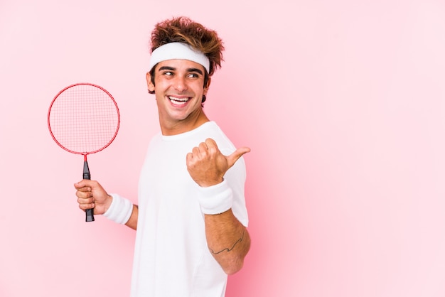 Jonge man spelen badminton geïsoleerde punten met duim vinger weg, lachen en zorgeloos.