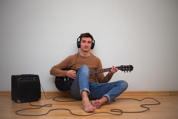 Jonge man spelen op een gitaar met muur op de achtergrond