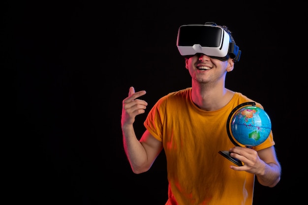 Jonge man spelen virtual reality globe houden op donkere ondergrond