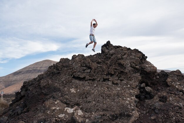 Jonge man springen op de top van een berg.