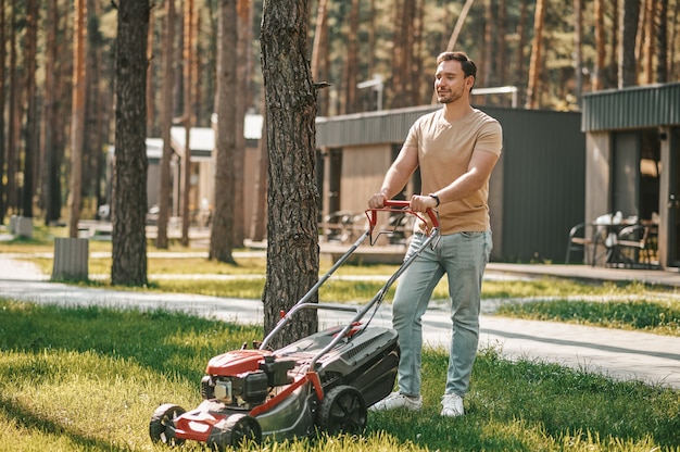 Jonge man staande met grasmaaier