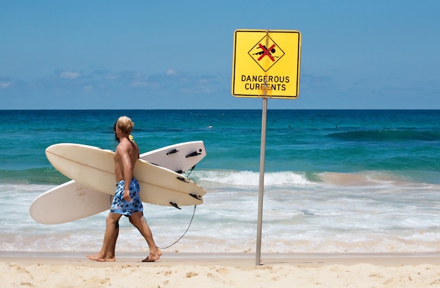 Jonge man staat op het punt te surfen met een groot bord dat verbiedt om in dat gebied te zwemmen