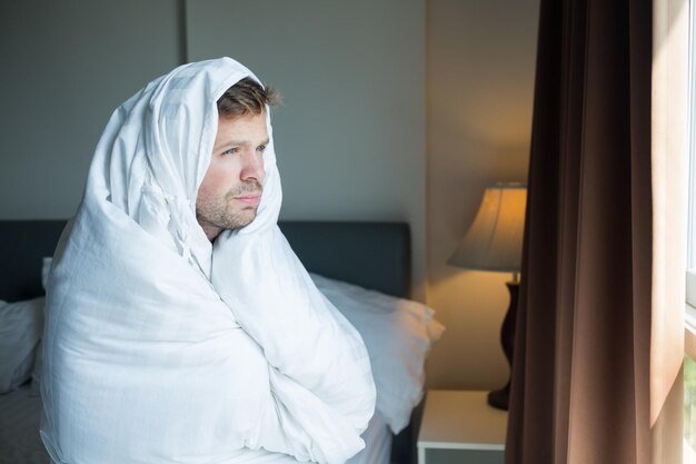 Jonge man staat 's ochtends bij het raam Hij staat vroeg op