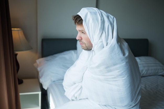 Jonge man staat 's ochtends bij het raam Hij staat vroeg op