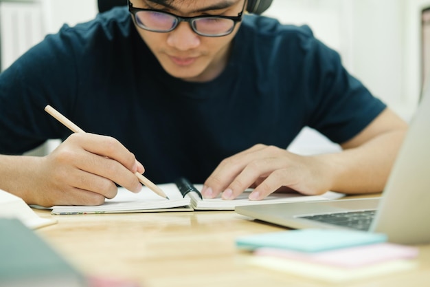 Jonge man studeert thuis achter de laptopcomputer