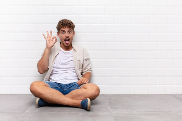 Jonge man succesvol en tevreden gevoel, glimlachend met wijd open geïsoleerde mond