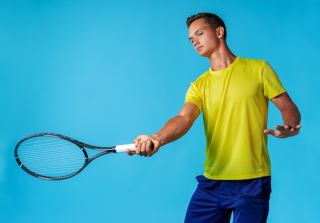 Jonge man tennisser in sportkleding poseren tegen blauw