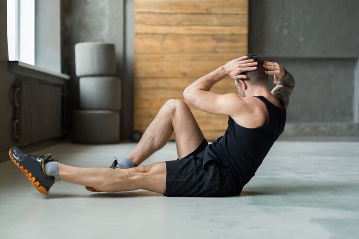 Foto jonge man training in fitnessclub. portret van een blanke man die oefening, sit-ups en cross crunches voor buikspieren maakt, binnenshuis trainen