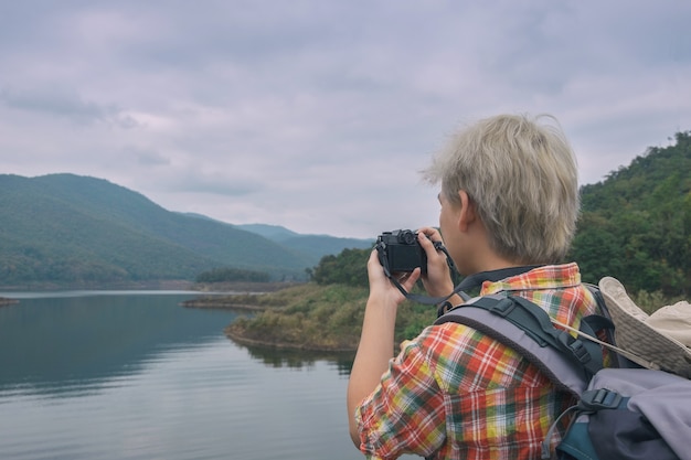 Jonge man trekker gebruik digitale camera nemen foto geniet van reizen met rugzak