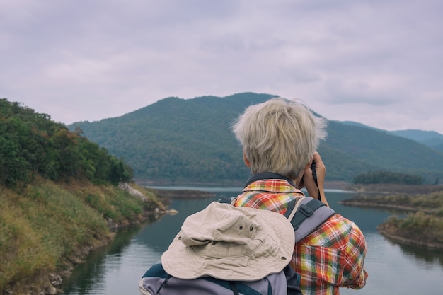 Jonge man trekker gebruik digitale camera nemen foto geniet van reizen met rugzak