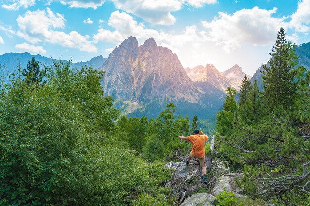 Jonge man trekking op de top van een groene berg genietend van het geweldige uitzicht op het landschap tijdens zonsondergang