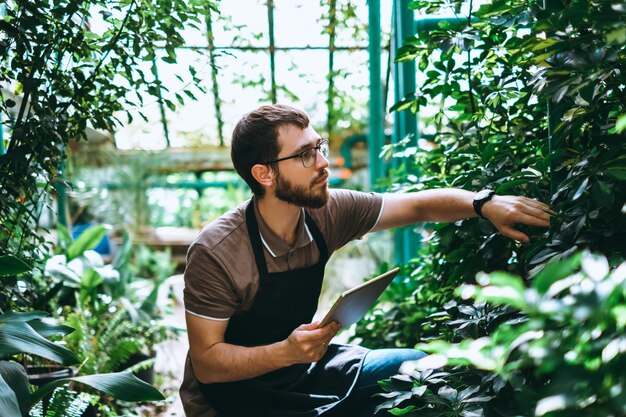 Jonge man tuinman met digitale tablet werken in een tuincentrum