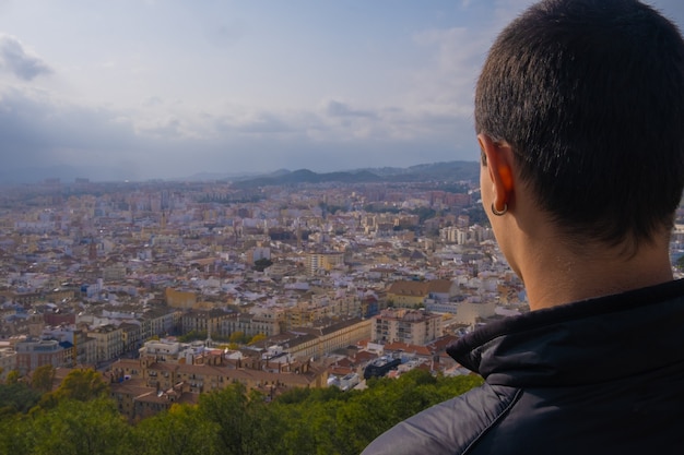 Jonge man van achteren kijkend naar de stad Malaga.