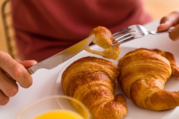 Jonge man van gemengd ras die 's ochtends croissants eet in een keuken