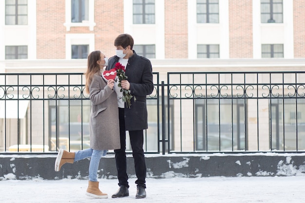 Jonge man verraste zijn vriendin met een boeket rozen en een hartvormige geschenkdoos in de stad