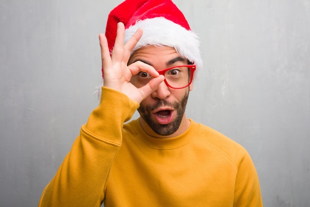 Jonge man vieren kerst dag houden geschenken zelfverzekerd doen ok gebaar op oog