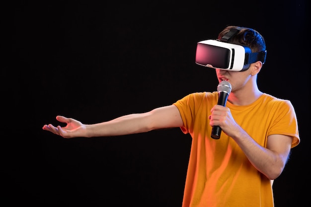 Jonge man virtual reality spelen en zingen op het donkere oppervlak