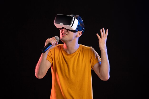 Jonge man virtual reality spelen en zingen op het donkere oppervlak