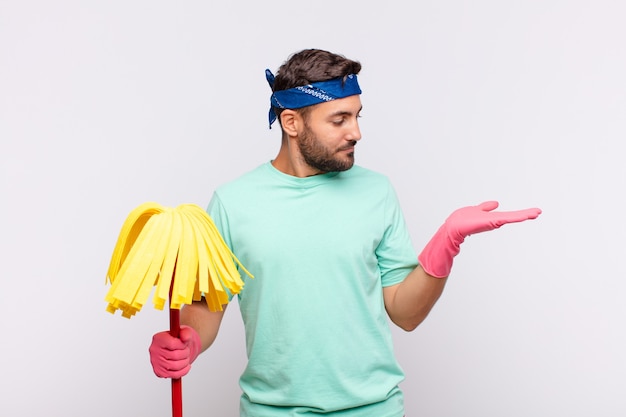 Jonge man voelt zich gelukkig en lacht nonchalant, kijkend naar een object of concept dat aan de zijkant wordt vastgehouden