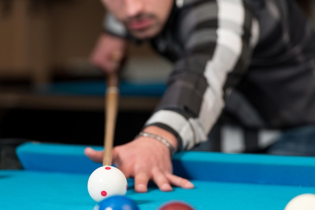 Jonge man voering om bal op pooltafel te raken