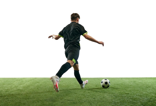 Jonge man voetballer in uniform spelen training dribbelen bal geïsoleerd op witte achtergrond