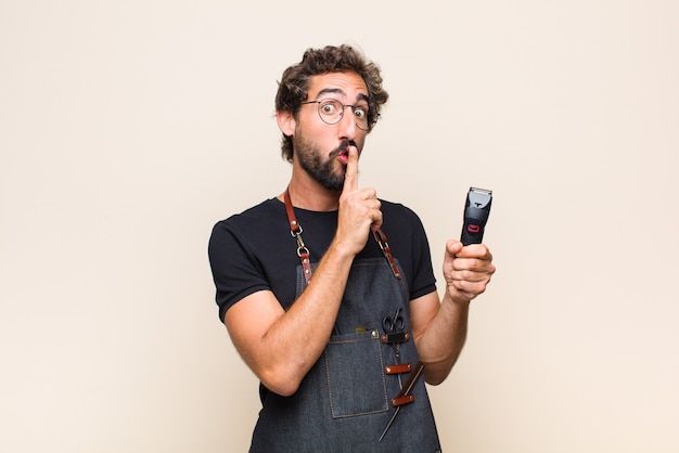 Jonge man vraagt om stilte en stilte, gebaart met de vinger voor de mond, zegt shh of houdt een geheim