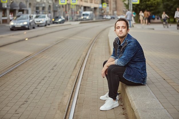 Jonge man wacht op tram bij een tramhalte.