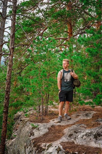 Jonge man wandelen door een dennenbos met enorme rotsen bedekt met mos
