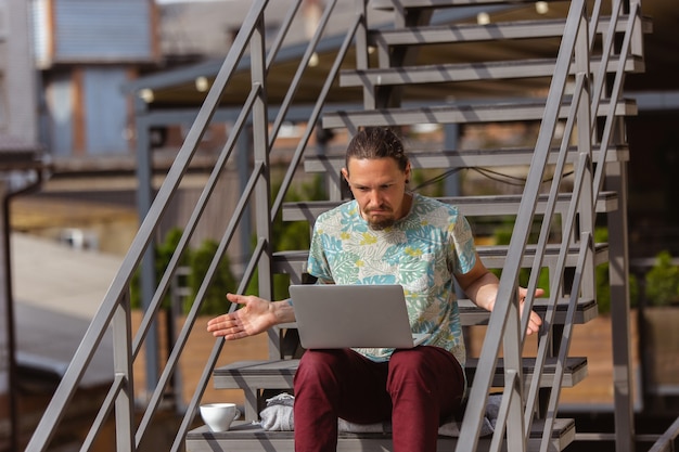 Foto jonge man zakenman op zoek naar werk met laptop buitenshuis