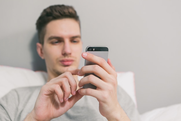 Jonge man zit aan de telefoon in bed