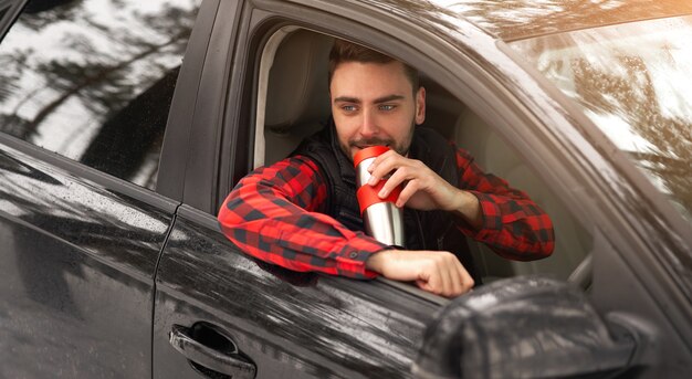 Jonge man zit achter het stuur van zijn auto