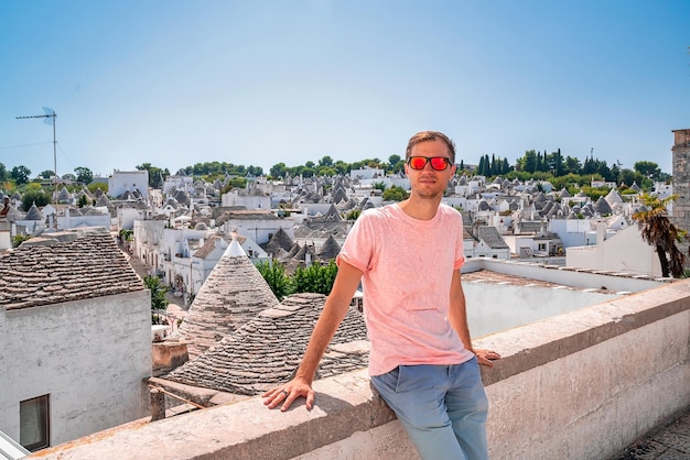 Jonge man zit bij de trulli-huizen in Arbelobello, provincie Bari, regio Puglia, Italië. Prachtig Italië, regio Bari.