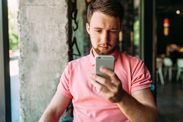 Jonge man zit in café met laptop en telefoon, werken, online winkelen, hipster