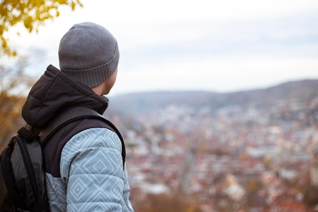 Jonge man zit met zijn rug te kijken naar het panoramische uitzicht over de stad