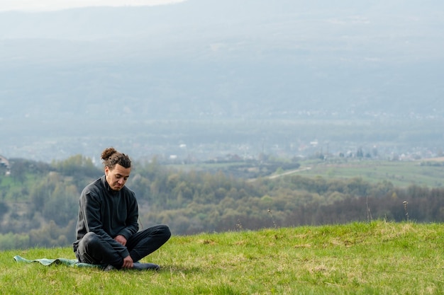 Jonge man zit op de bergtop