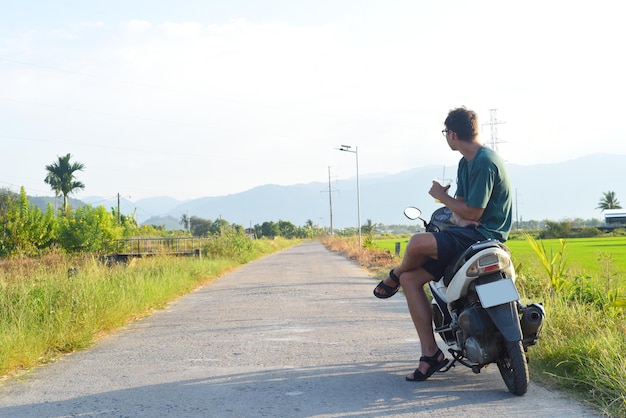 Jonge man zit op een motor tussen rijstvelden in Vietnam