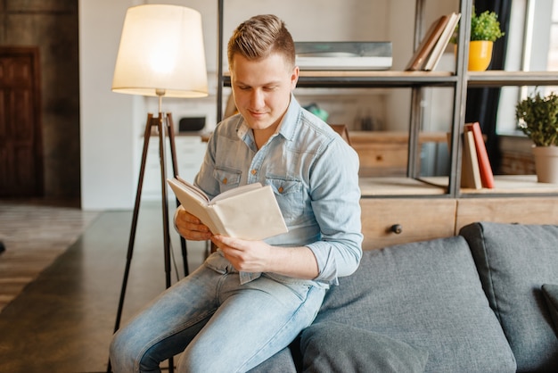 Jonge man zittend in de bank en een boek lezen