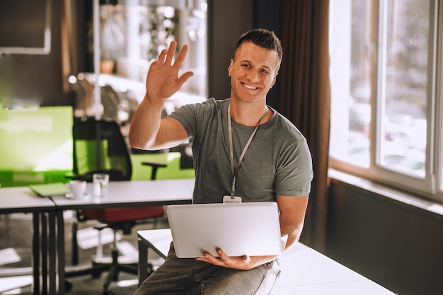 Jonge man zittend op de tafel met een laptop