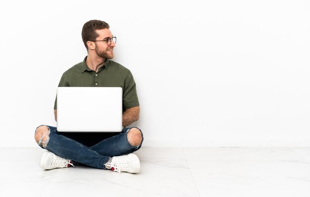 Jonge man zittend op de vloer kijkend naar de zijkant