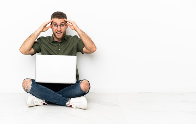 Jonge man zittend op de vloer met een verbaasde uitdrukking