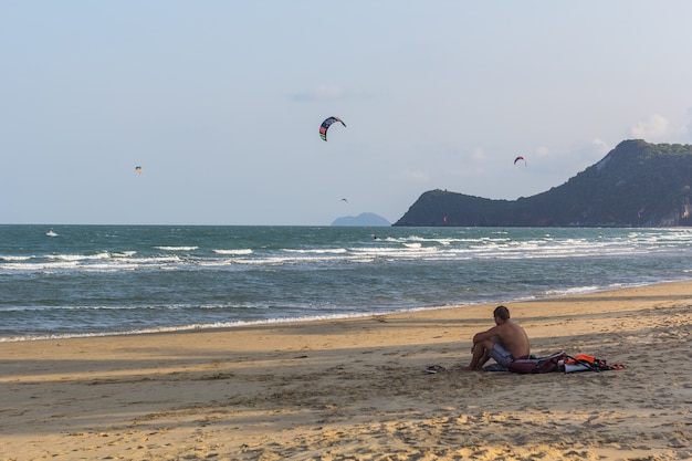 Jonge man zittend op het strand in de avond.