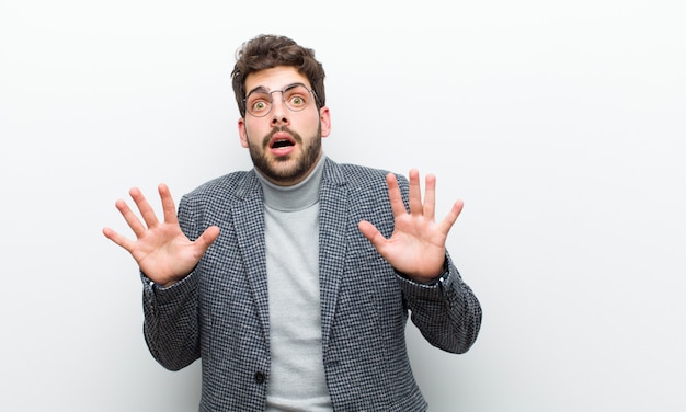 Jonge manager man gevoel stom en bang, bang voor iets beangstigend, met handen open voor zeggen zeggen blijf weg