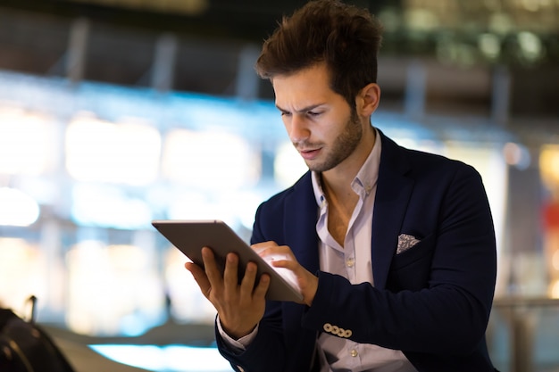 Jonge manager met behulp van een digitale tablet buiten in een moderne stad &#39;s nachts