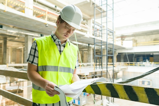 Jonge mannelijke architect bij een bouwwerf