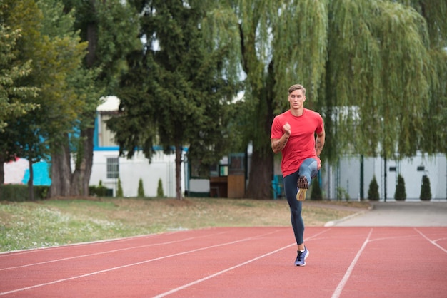 Jonge mannelijke atleet die op het goede spoor loopt