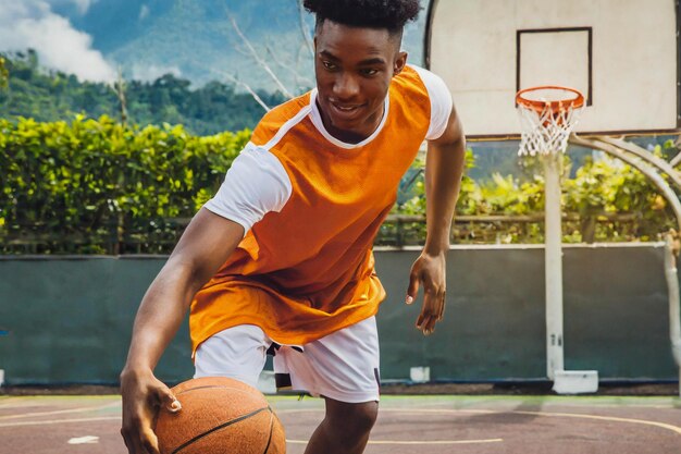 Jonge mannelijke basketbalspeler dribbelt de bal op het basketbalveld in actie