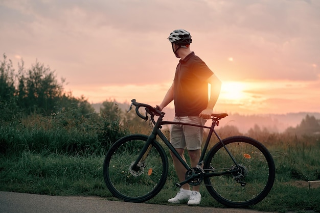 jonge mannelijke fietser met zijn grindfiets rijden op het platteland vooraanzicht concept van actieve sporten en een gezonde levensstijl